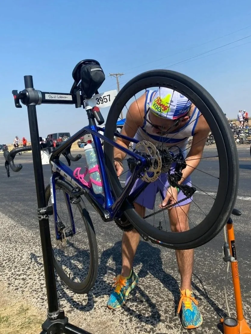 Austin working on a bicycle in a repair stand at a race
